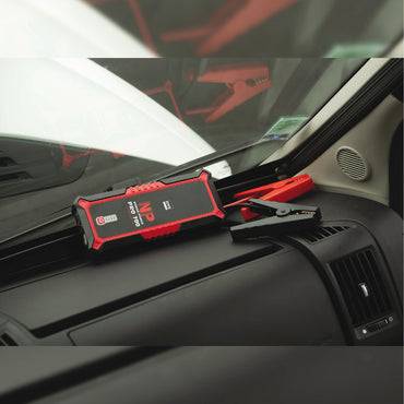 GYS Nomad Power 700 028838 2000A Lithium Jump Pack resting on a vehicle dashboard with attached jumper cables, ideal for 12V vehicle emergency starts.
