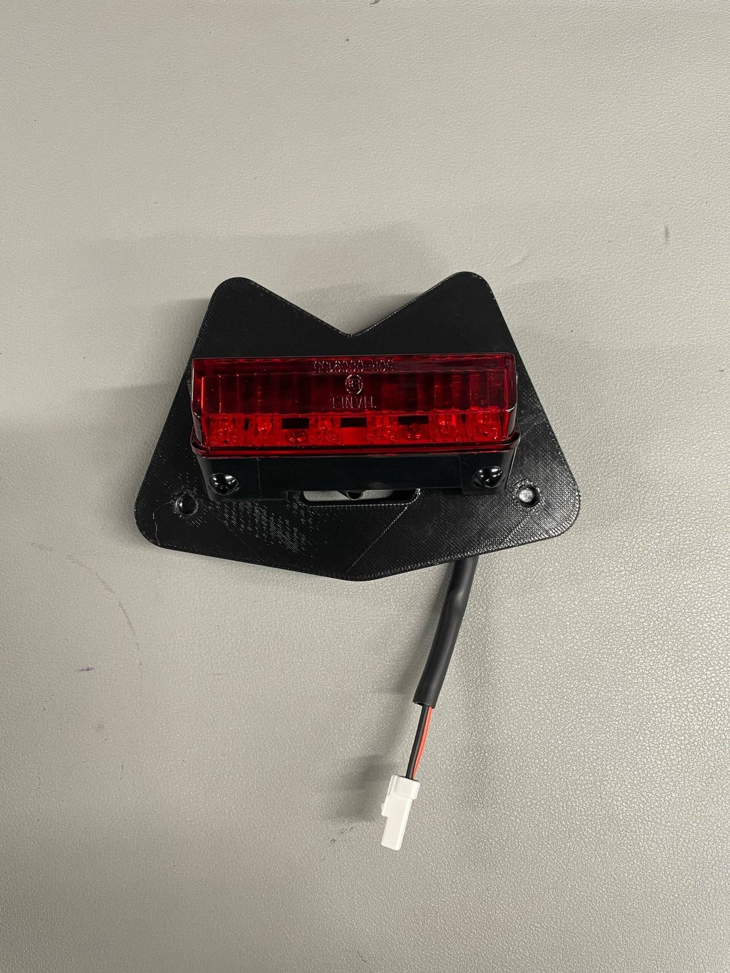 Aprilia RS660 Rain Light Bracket with red LED light and Ducati-type 2-pin connector, mounted on a black subframe-compatible plate.