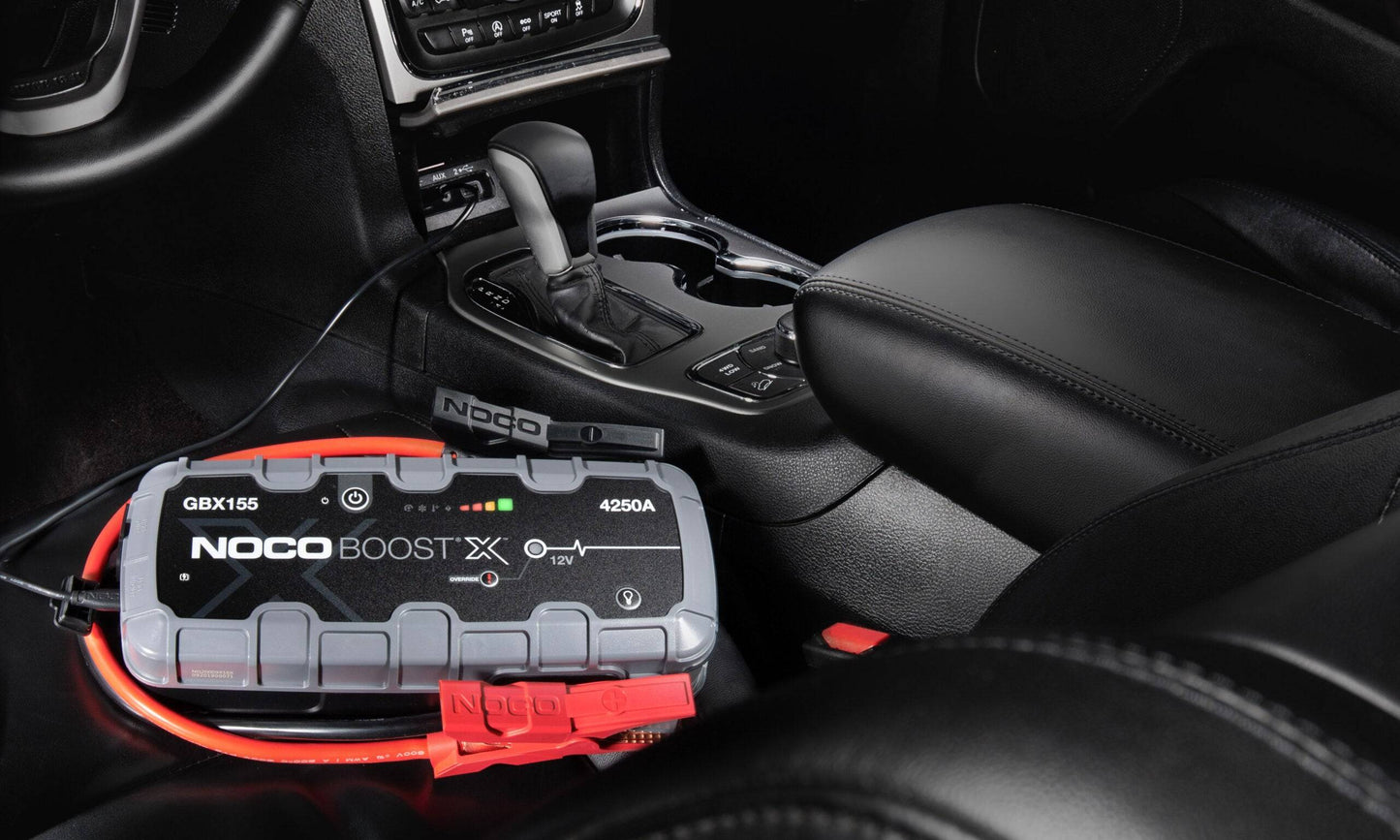 Noco Boost X GBX155 4250A jump starter inside a vehicle cabin, showcasing its compact design and versatility for in-car emergency power solutions.