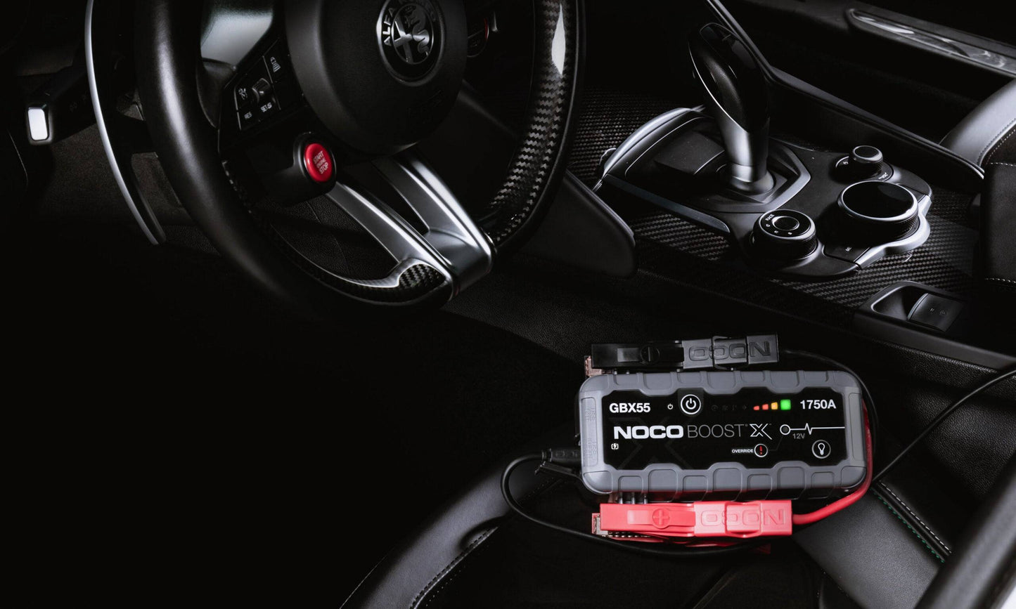Noco Boost X GBX55 Ultrasafe Lithium Booster 1750A connected inside a car, showcasing compact design and high power for jump-starting gas and diesel engines.