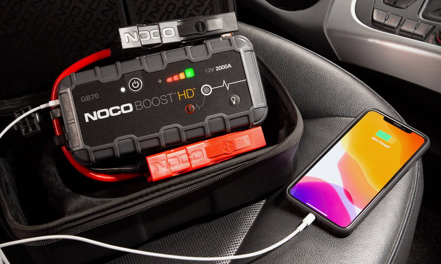 Noco GB70 Boost HD 12V 2000A Jump Starter charging a smartphone via USB, highlighting multifunctional use.
