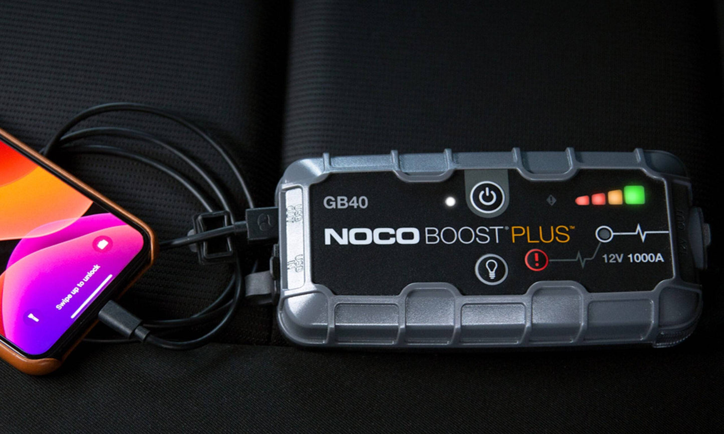 Noco GB40 Boost Plus 12V 1000A Jump Starter charging a smartphone.